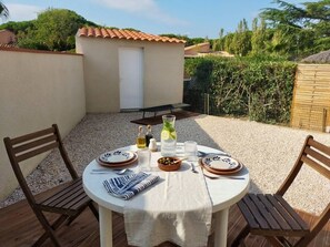 Una mesa redonda con sillas, una mesa pequeña y una puerta en un patio.
