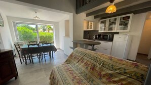 A compact living space with a dining area, kitchenette, and a bed with a floral bedspread.
