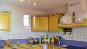 A kitchen with yellow cabinets, a purple countertop, and a dining area with a pink tablecloth. - 3-room villa with air conditioning, parking, and pets allowed in Saint-Pierre-la-Mer (Fleury-Saint-Pierre-la-Mer)