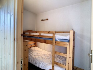 A bunk bed room with wooden frames and white bedding.