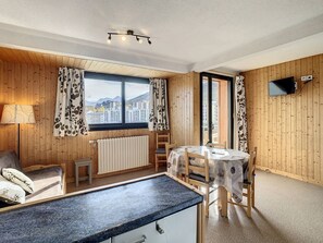 A cozy room with wooden walls, a bed, a desk, a chair, a table, a TV, and a window with curtains. - Pleasant 35m² apartment in La Toussuire, 1 bed, 50m from slopes, Free Wi-Fi (La Toussuire)