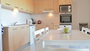 A modern kitchen with wooden cabinets, a white dining table, and chairs.