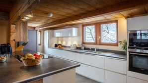 A modern kitchen with a large island, white cabinetry, and a built-in oven. - Chalet Colombine - luxury base 15p indoor pool & spa, cinema - OVO Network (Thônes)