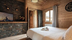 A cozy bedroom with a stone wall, wooden ceiling, and a bed with a tray of breakfast items. - Chalet Le Petit Mazot - romantic break for 4 close to slopes - OVO Network (La Clusaz)