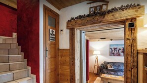 A wooden staircase leading to a room with a red wall, a wooden door with a WiFi sign, and a painting of cows on the wall. - Chalet Le Petit Mazot - romantic break for 4 close to slopes - OVO Network (La Clusaz)