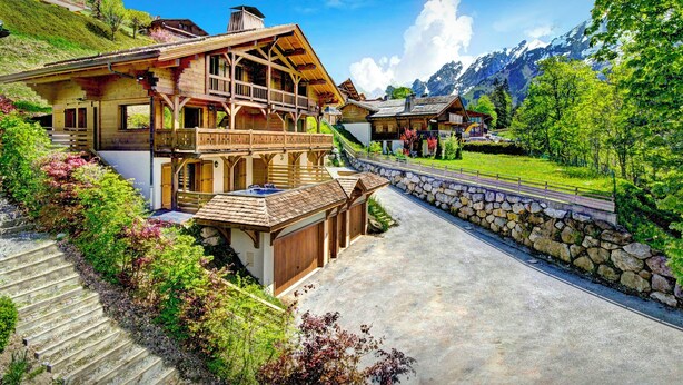 Una cabaña tradicional con fachada de madera, una escalera de piedra y vistas a una cordillera.