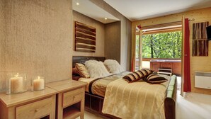 Un dormitorio con cama, mesitas de noche, ventana con vista a follaje y cabecera de madera.