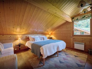 Une chambre confortable dans un chalet en bois, avec un lit, des lampes de chevet, une fenêtre donnant sur un beau paysage et une petite table.