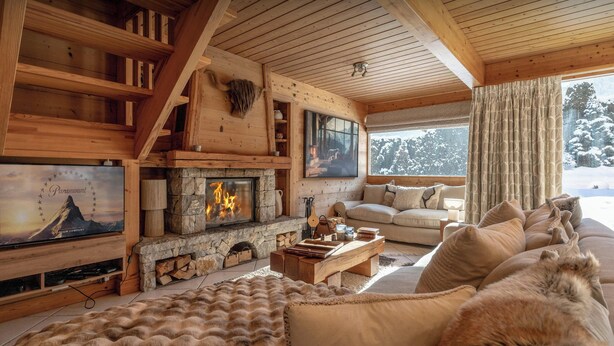 A cozy cabin interior with a stone fireplace, a sofa, and a television. - Chalet J'Elage - family base 10p, open fire & mountain views - OVO Network (St Jean de Sixt)