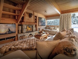 Ein gemütliches Blockhaus-Interieur mit Kamin, Sofa und Fernseher.