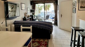 Habitación de hotel con cama, escritorio, silla, televisor y balcón con vistas a palmeras.