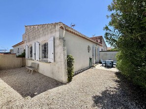 Un bĂątiment Ă lâextĂ©rieur blanc, avec un toit recouvert de tuiles et une cour intĂ©rieure en gravier.