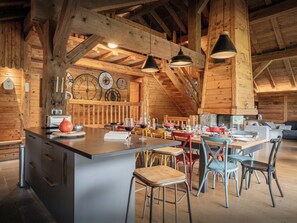 Un interior rústico de madera con una isla central, varias mesas y sillas.