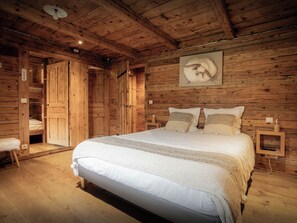 Un dormitorio de cabaña de madera con una cama, dos mesitas de noche y un cuadro colgado en la pared.