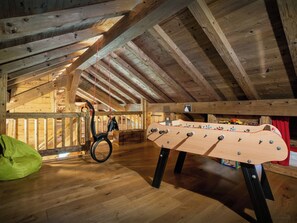 Habitación estilo loft con mesa de fútbol de mesa y una silla colgante.