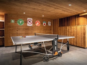 A ping pong table in a room with wooden walls and ceiling, a sign indicating room number 7, and a no-smoking sign.