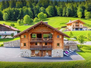Una cabaña de madera con balcón, base de piedra y vistas a un valle verde.