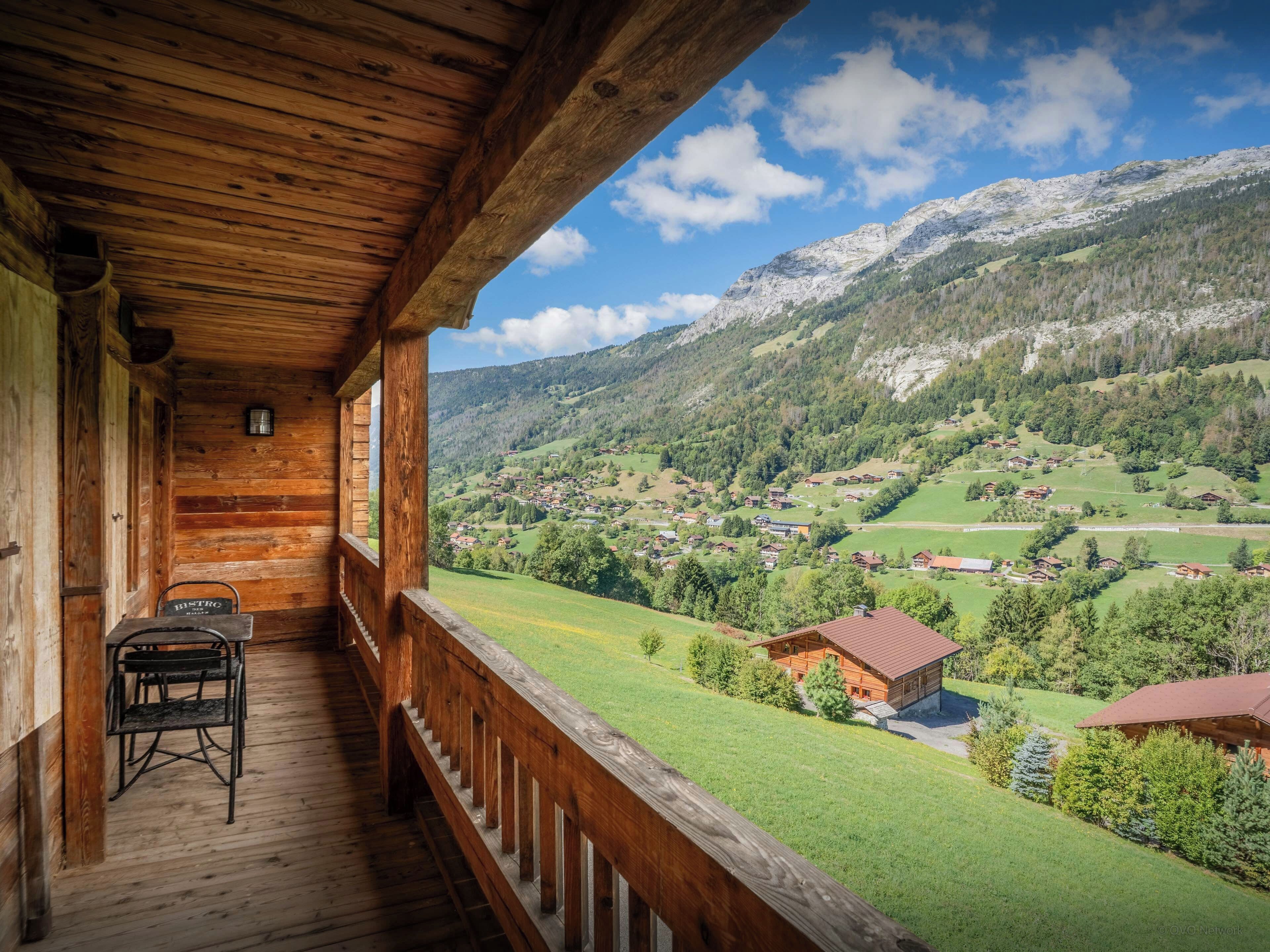 A wooden cabin with a balcony overlooking a mountainous landscape.
