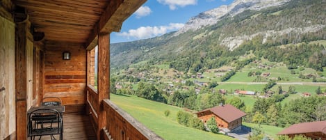 Une cabane en bois dotée d’un balcon donnant sur un paysage montagneux.