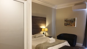 Ein Hotelzimmer mit Bett, Nachttisch, Schreibtisch, Stuhl, Lampe und einem Bild an der Wand.