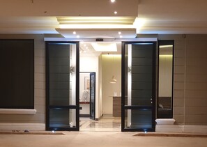 Un hall d'hôtel au design moderne, doté d'une entrée avec une porte en verre, d'un comptoir d'accueil et d'un intérieur bien éclairé.