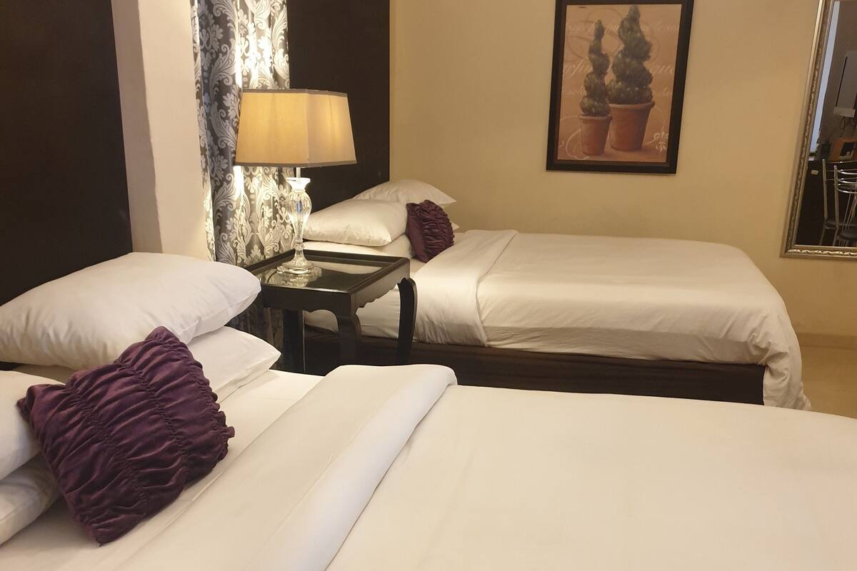 Een hotelkamer met twee bedden, een nachtkastje, een lamp en een lijst aan de muur.