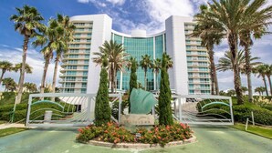 A modern hotel with a curved facade, multiple balconies, and a central water feature.