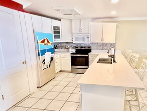 Una cocina con gabinetes blancos, un microondas, un horno y un lavamanos.