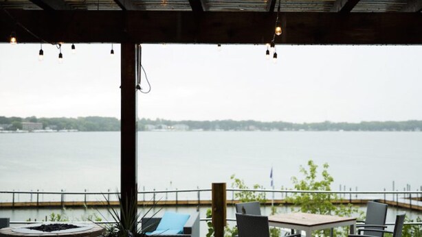 Een overdekt terras met uitzicht op een meer en een verre oever.