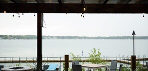 A covered outdoor seating area with a view of a lake and distant shoreline.