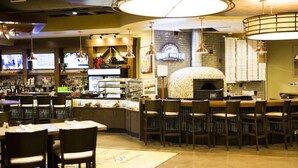 Een bar met verschillende zithoeken, een toonbank met presentatie en een pizzaoven.