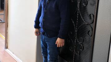Un niño de pie junto a una puerta con una celosía metálica decorativa.