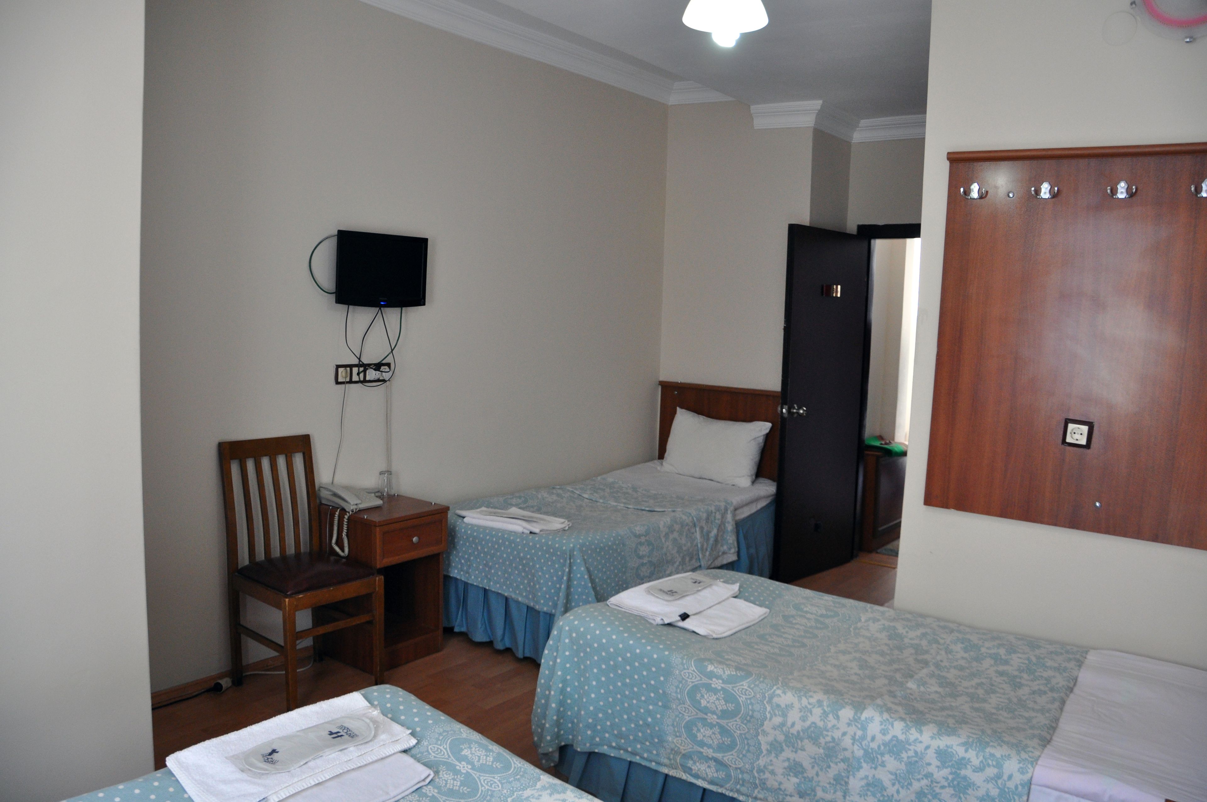 Una habitación con dos camas, un escritorio, una silla, un televisor y un armario.