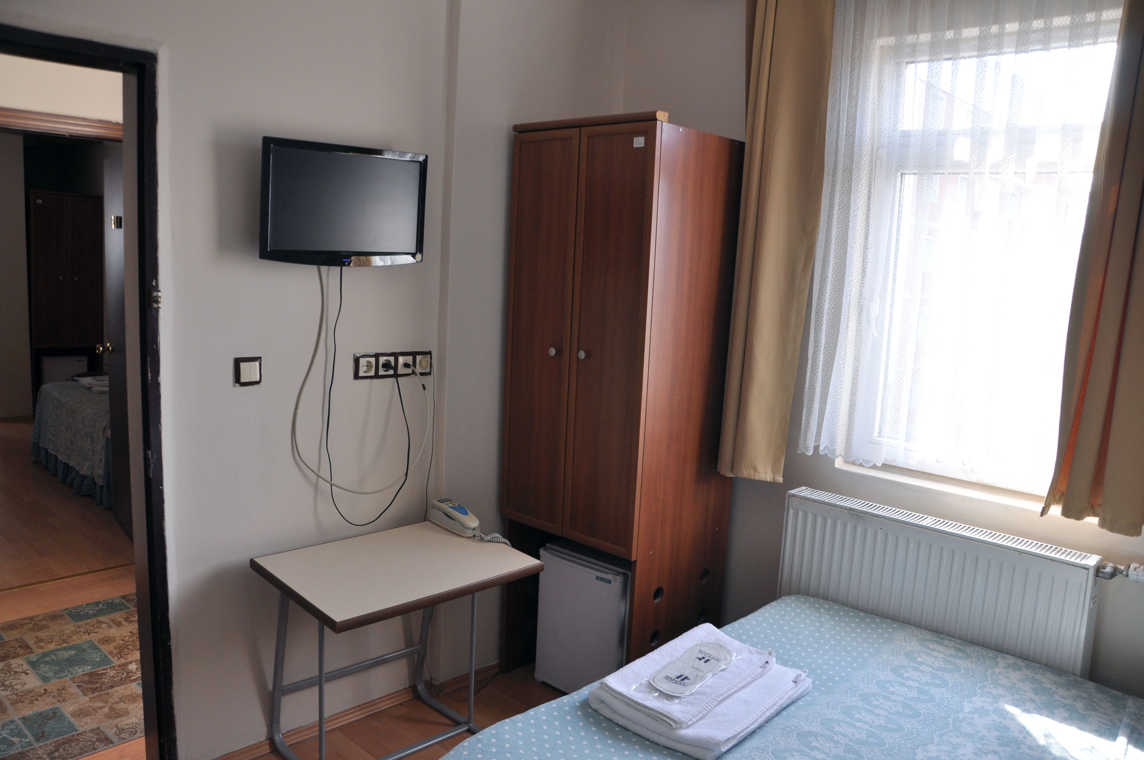 A small room with a bed, a desk, a television, and a wardrobe.