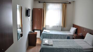 A hotel room with two beds, a wardrobe, a desk, a chair, a television, and a window with curtains.
