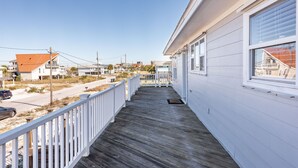 A wooden deck with a white railing, leading to a building with a red roof.