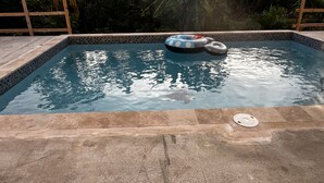 En pool med kakel runt kanten, en flytande badring och ett avloppsskydd.