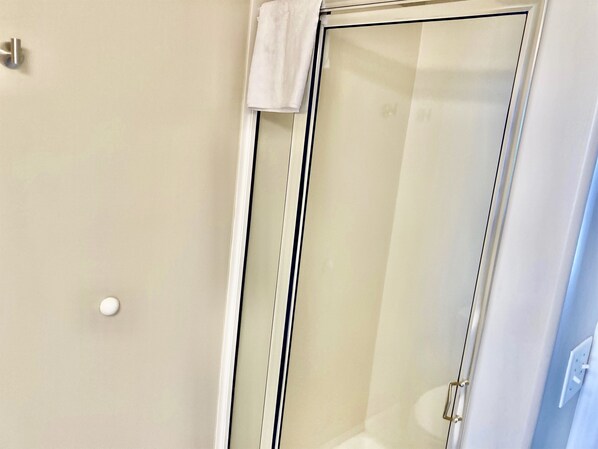 A glass shower enclosure with a white towel hanging on the door handle.
