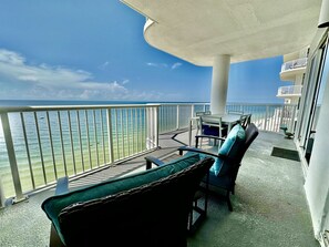 A balcony with a view of the ocean, a table with chairs, and a railing.
