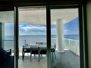 Enjoy the ocean view from this balcony with a table and chairs.