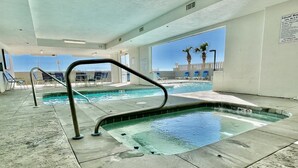 An indoor pool area with clear water, a lifeguard station, and lounge chairs.