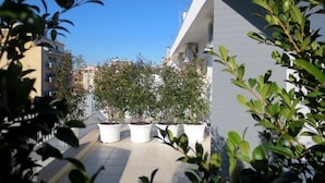 A rooftop terrace with potted plants and a view of surrounding buildings. - Gatto Bianco Le Terrazze (Bari)