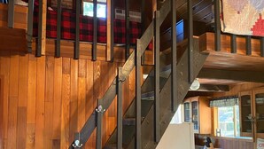 A wooden staircase with a checkered table and chairs in the lower level.