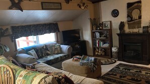 Een gezellige woonkamer met een bank, voetenbankje en een open haard.