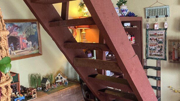 Een houten trap met een piano en een stoel eronder.