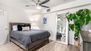Een slaapkamer met een bed, plafondventilator en een kamerplant.