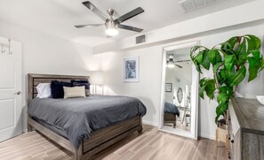 Een slaapkamer met een bed, plafondventilator en een kamerplant.