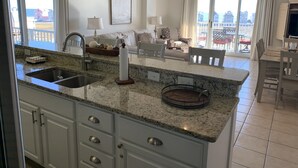 A kitchen with granite countertops, a sink, and a dining area with a table and chairs.