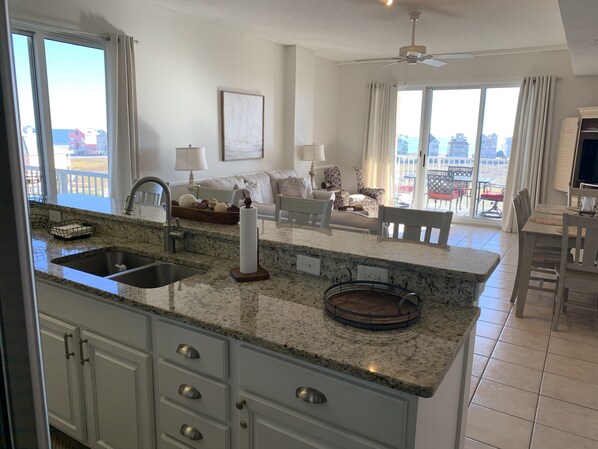 A kitchen with granite countertops, a sink, and a dining area with a table and chairs.