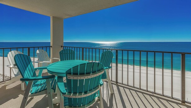 Een balkon met uitzicht op de oceaan, met een tafel en stoelen.